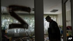 Військовик ЗСУ інспектує будівлю дитячого садочка у звільненому після російської окупації села Капитолівка поблизу Ізюма, Харківщина, 25 вересня 2022. Численні свідчення підтверджують факти тортур російськими військами цивільних українців. AP Photo/Evgeniy Maloletka