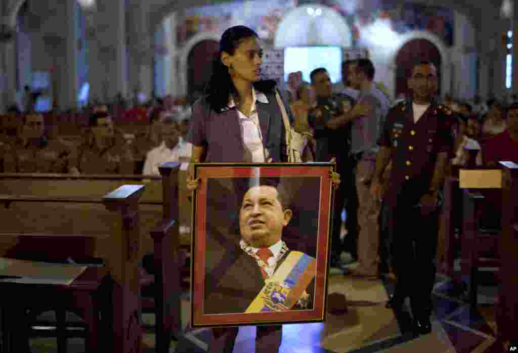 A woman carries an image of Chavez before a mass in support of him in Havana, Cuba, December 13, 2012. 
