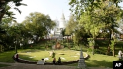 ស្រ្តី​ពីរ បី​នាក់ អង្គុយ​នៅ​លើ​គែម​នាឡិកា​ដ៏​ធំ​នៅ​ក្នុង​បរិវេណ​រមណីយដ្ឋាន​វត្តភ្នំ ដែល​ស្ថិត​នៅក្នុង​រាជធានី​ភ្នំពេញ នៃ​ប្រទេស​កម្ពុជា។