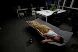 Ma Zhenguo, a system engineer at RenRen Credit Management Co., sleeps on a camp bed at the office after finishing work early morning, in Beijing, China, April 27, 2016.