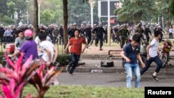 People run as riot police officers (back) try to disperse protesters against a chemical plant project in Maoming, Guangdong province, March 31, 2014.