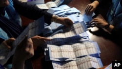 FILE - Afghan election workers count ballots during the presidential election, at a polling station in Kabul, Sept. 28, 2019. International pressure seems to have taken the steam out of a dispute that followed the election.