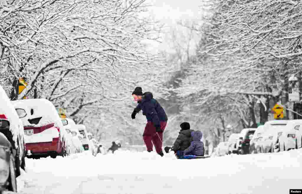 A man pulls children in a sled along a street after the first significant snowfall of the season in Montreal, Quebec, Canada, Dec. 8, 2024.