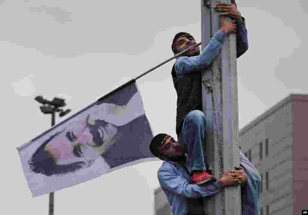 A supporter of the pro-Kurdish Peoples&#39; Democratic Party (HDP) is helped to climb a pole with a flag of imprisoned Kurdish rebel leader Abdullah Ocalan, during a rally in Istanbul, Turkey, June 8, 2015, a day after the elections.