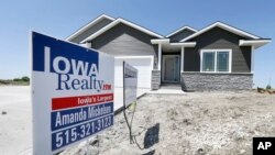 A sign sits in front of a new home for sale in West Des Moines, May 21, 2014, Iowa.