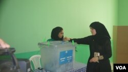 Seorang warga Afghanistan memasukkan surat suaranya ke dalam kotak di sebuah TPS di wilayah Mazar-e-Sharif. Meski diancam serangan Taliban, warga Afghanistan mendatangi TPS-TPS untuk memilih presiden baru negara itu, Sabtu (14/6).