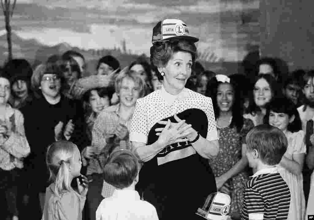 First lady Nancy Regan models a school cap and holds a school shirt presented to her during her visit to Chicago's Latin School, May 14, 1982. 