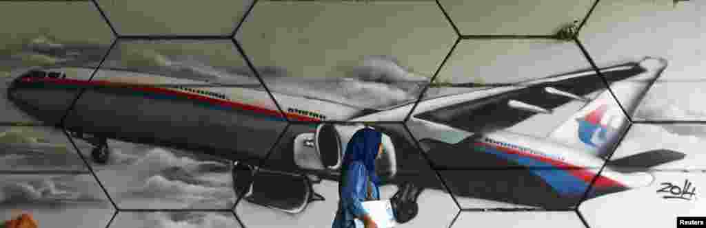 A woman walks past graffiti of Flight MH370 in Kuala Lumpur, April 15, 2014.