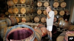 Winemakers, like this man, often store wine in barrels, 2014, Napa, California. (AP Photo/Eric Risberg) 