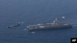 FILE - The USS Abraham Lincoln aircraft carrier and a U.S. Air Force B-52H Stratofortress conduct joint exercises in the Arabian sea, June 1, 2019.