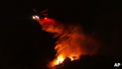 Хеликоптер испушта вода врз пожар што гори долж автопатот Интерстејт 405, на 23 јануари 2025, во Лос Анџелес.