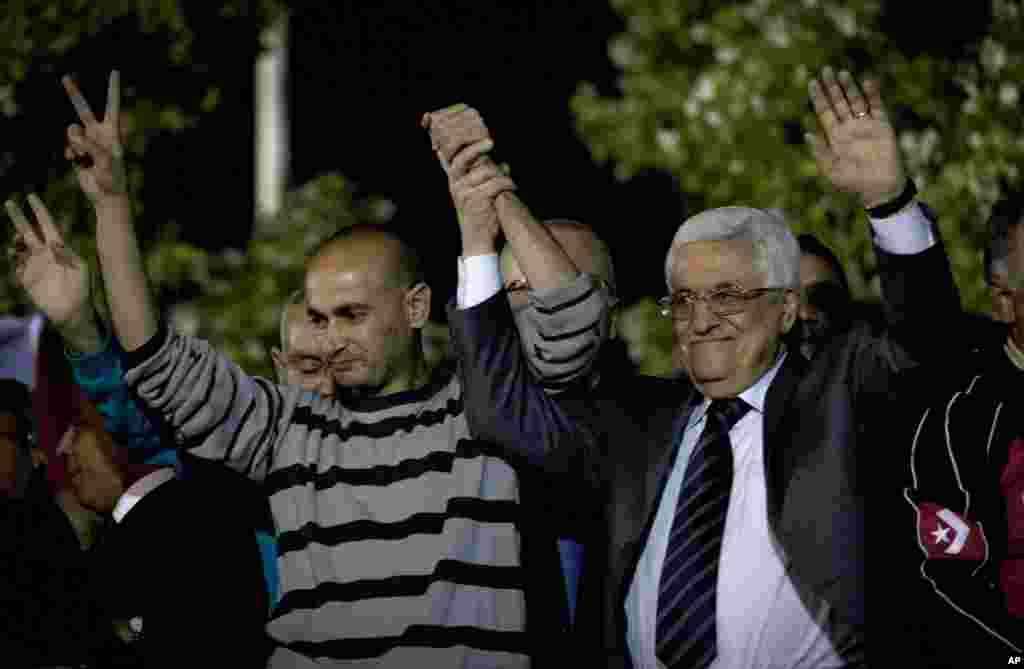 Palestinian President Mahmoud Abbas holds the hand of a freed prisoner during a welcome ceremony at the Palestinian Authority headquarters, in the West Bank city of Ramallah, Oct. 30, 2013. 