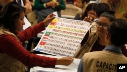 Election workers look at a ballot during a partial recount of presidential and congressional elections in Tegucigalpa, Honduras, Dec. 5, 2017. 
