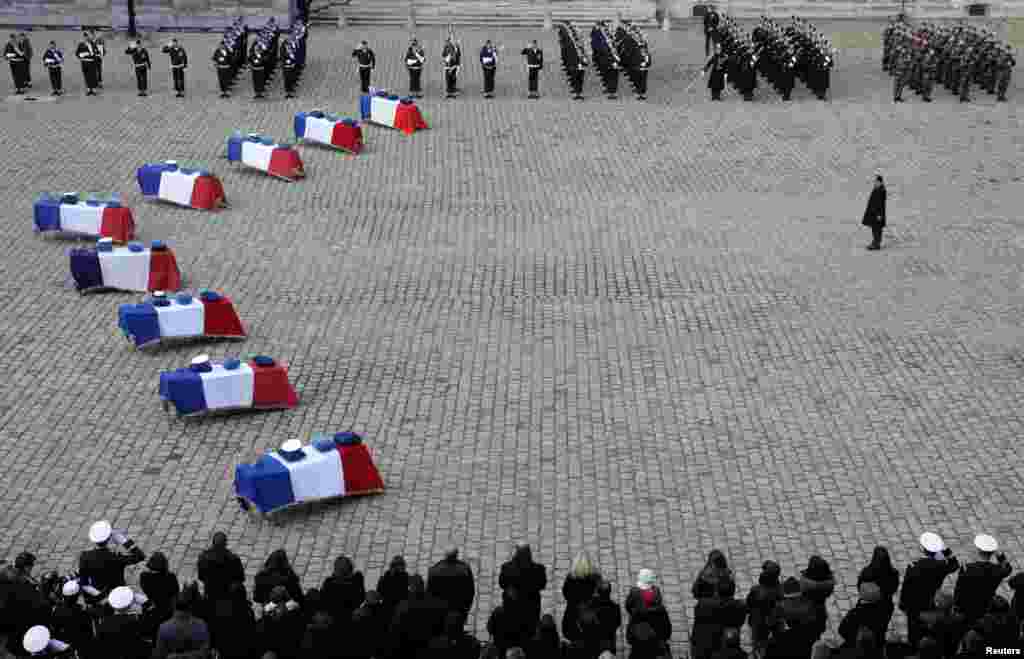 French President Francois Hollande pays his respect to the flag-draped coffins of the nine French Air Force personnel in the Invalides courtyard during a ceremony in Paris. The air force personnel died in an accident at a base used for NATO training where a Greek F-16 fighter plane crashed after taking off from Albacete, Spain, about 250 kilometers southeast of Madrid on Jan. 26, 2015.