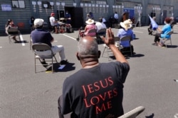 FILE - Church parishioners sit socially distanced at a prayer vigil for racial justice at Immaculate Conception Catholic Church in Seattle, July 19, 2020.