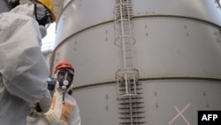 Japanese Economy, Trade and Industry Minister Toshimitsu Motegi (R) in a radiation protection suit inspects a contaminated water tank, found to be have a huge leak of radioactive water, August 26, 2013. 