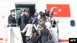 PM Turki Ahmet Davutoglu (kiri) berada di tangga pesawat bersama para sanders yang dibebaskan oleh ISIS di bandara Sanliurfa, selatan Turki dekat perbatasan Suriah (20/9).