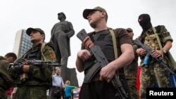 Pasukan separatis pro-Rusia bersenjata di depan monumen Vladimir Lenin di Donetsk, Ukraina timur (21/6).