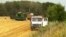  A John Deere combine harvests, threshes and pumps wheat into a waiting truck on fields managed by UkrLand Farming, July 21, 2012. Wheat from these fields may end up in Chinese bread next year. (VOA/J. Brooke)