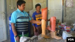 Kyaw Win and his colleague, both former Karenni fighters who lost legs to landmines, look at prosthetic legs in their workshop in Loikaw. (P. Vrieze/VOA)