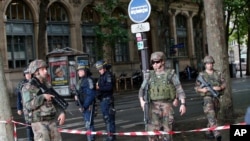 FILE - Police officers and soldiers seal off the access to Notre Dame cathedral after a man attacked officers with a hammer in front of the famous landmark in Paris, June 6, 2017.
