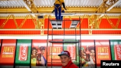 Seorang pekerja tengah membetulkan lampu di atas poster sponsor FIFA di luar stasiun kereta api di dekat stadion World Cup di Sao Paulo, Brazil (Foto: dok).