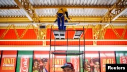 រូប​ភាព​ឯកសារ៖ ជាង​កំពុង​បំពាក់​ភ្លើង​ដាក់​លើ​ផ្ទាំអ​ផ្សាយ​ពាណិជ្ជកម្ម​ការឧបត្ថម្ភ​ FIFA នៅ​ក្រៅ​ស្ថានីយ​រថភ្លើង​មួយ​​ក្បែរ​ពហុកីឡាដ្ឋាន​សម្រាប់​ការទាត់​បាល់​ពិភពលោក​ ក្នុង​ទីក្រុង​​ Sao Paulo ។