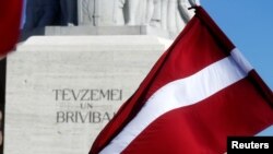 Latvia's national flag flutters next to the Freedom monument in Riga, Latvia, March 16, 2018. 