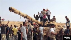 Pejuang revolusi merayakan kemenangan mereka setelah menguasai sebuah tank dari kubu pro-Gaddafi di Sirte, Libya (20/9).
