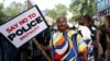 FILE - A protester holds a placard during an anti-police brutality protest, in Abuja, Nigeria, Oct. 20, 2021.