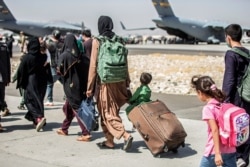 Families walk towards their flight during evacuations at Hamid Karzai International Airport, in Kabul, Afghanistan, Aug. 24, 2021, in this photo provided by the U.S. Marine Corps. (Sgt. Samuel Ruiz/U.S. Marine Corps via AP)