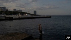 Seorang anak laki-laki menyelam ke dalam air di objek wisata pantai populer di sepanjang pantai Laut Hitam di Odesa, Ukraina, Minggu, 23 Juli 2023. (Foto: AP)