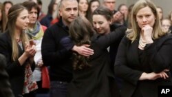 Former gymnast Rachael Denhollander, center, is hugged after giving her victim impact statement before the sentencing of sports doctor Larry Nassar, in Lansing, Michigan, Jan. 24, 2018. 