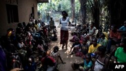 FILE - A volunteer carries daily food rations in a camp for internally displaced persons (IDPs) fleeing the conflict in Kikwit, Kasai province, DRC, June 7, 2017. 