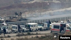 Forces loyal to Syria's President Bashar al-Assad sit on a tank as a convoy of buses and other vehicles bringing people out of eastern Aleppo turns back in the direction of the besieged rebel enclave, Syria, Dec. 16, 2016. 