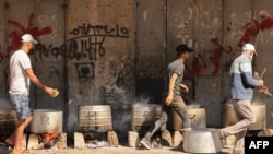 Orang-orang memasak dengan kayu bakar untuk menyediakan makanan bagi pengungsi Palestina di tengah menipisnya pasokan bahan bakar minyak dan gas pada saat serangan Israel di Khan Yunis, selatan Jalur Gaza, 15 Oktober 20223. (Foto: MAHMUD HAMS / AFP)