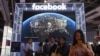 FILE - Visitors pass by the booth for social media giant Facebook at the China International Import Expo in Shanghai, Nov. 6, 2019.