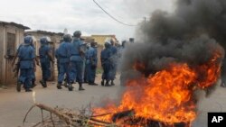 Des policiers à côté d'un pneu brûlé lors d'une manifestation à Bujumbura, Burundi. 26 avril 2015.