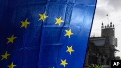Bendera Uni Eropa dipegang oleh seorang demonstran, dengan latar belakang Menara Victoria, di luar Istana Westminster, di London, Senin, 14 Desember 2020, selama protes saat pembicaraan perdagangan Brexit berlanjut. (Foto: AP/Alberto Pezzali)