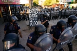 A sign set up by mourning fans reads in Spanish, "Thank You God for Everything," as police block their access to the Jardin de Bellavista cemetery during the burial of Diego Maradona in Buenos Aires, Argentina, Nov. 26, 2020.