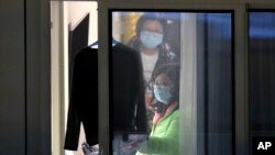 Passengers from the cruise ship "World Dream" docked at Kai Tak cruise terminal, gesture in Hong Kong, Saturday, Feb. 8, 2020. The cruise ship "World Dream" with approximately 1,800 passengers remained quarantined in Hong Kong's Victoria Harbour on…