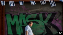 A man without a face mask walks by a "mask" graffiti in downtown Tel Aviv, Israel, April 18, 2021.