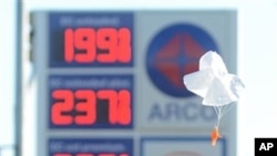 Joanna Alvarez plays with a toy parachute man at the Arco gas station parking lot where gasoline is posted at $1.99 a gallon in Oak Hills, Calif, on Wednesday, Feb., 24, 2016. (David Pardo, Victor Valley Daily Press via AP)
