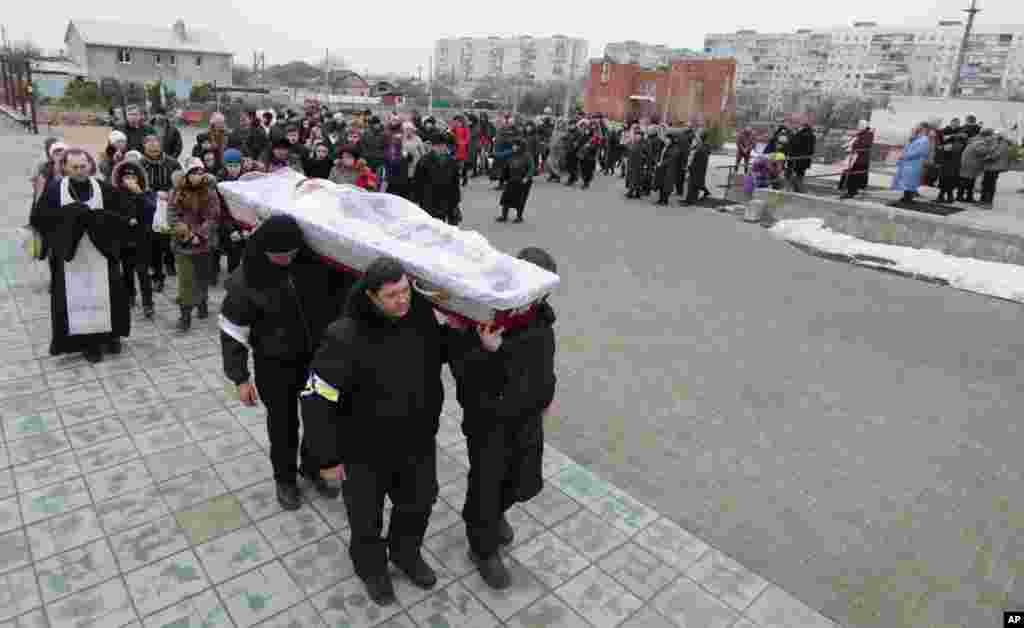 Ukrainians carry a coffin bearing the body of Olga Abdurashitiva, who was killed Saturday during an attack in Mariupol, Ukraine, Jan. 26, 2015.