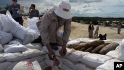 FILE - In this July 31, 2013 photo, a Vietnamese deminer hands unexploded ordinance to a colleague ahead of a controlled detonation in Vinh Thai, Vietnam.