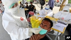 Seorang pekerja medis mengambil sampel usap hidung dari seorang pria selama tes virus corona wajib bagi mereka yang bepergian antara Pulau Madura dan Surabaya. (Foto: AP)