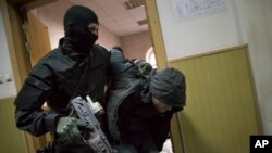 Police escort a man believed to be one of five suspects in the killing of Boris Nemtsov in a court room in Moscow, Russia, Sunday, March 8, 2015.