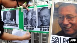FILE - A protester affixes pictures of Chinese writer Mo Yan (L) and Chinese dissident Liu Xiaobo (R) to a gate during a demonstration in front of the Chinese liaison offices demanding the release of Chinese Liu in Hong Kong.