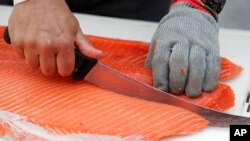 Jim Lagucik, dari Trident Seaffods, memotong raja salmon asal Copper River, 18 Mei 2018 di Bandara Internasional Seattle-Tacoma di Seattle, Washington (foto: AP Photo/Ted S. Warren)