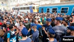 ក្រុម​ជន​ទេសន្តរប្រវេសន៍​ប្រឈម​មុខ​ដាក់គ្នា​ជាមួយ​នឹងប៉ូលិសហុងគ្រី នៅឯស្ថានីយ៍​រថភ្លើង​ធំមួយ​ក្នុង​ទីក្រុង​ប៊ុយដាប៉ែស ប្រទេស​ហុងគ្រី កាលពីថ្ងៃទី១ ខែកញ្ញា ឆ្នាំ២០១៥។